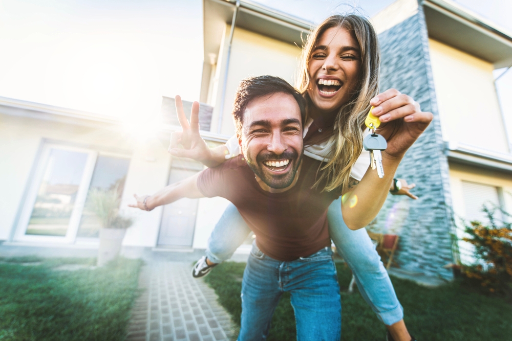 Joyful couple smiling outside their new home, holding house keys and celebrating a successful property sale in San Diego – Sell My House Fast San Diego