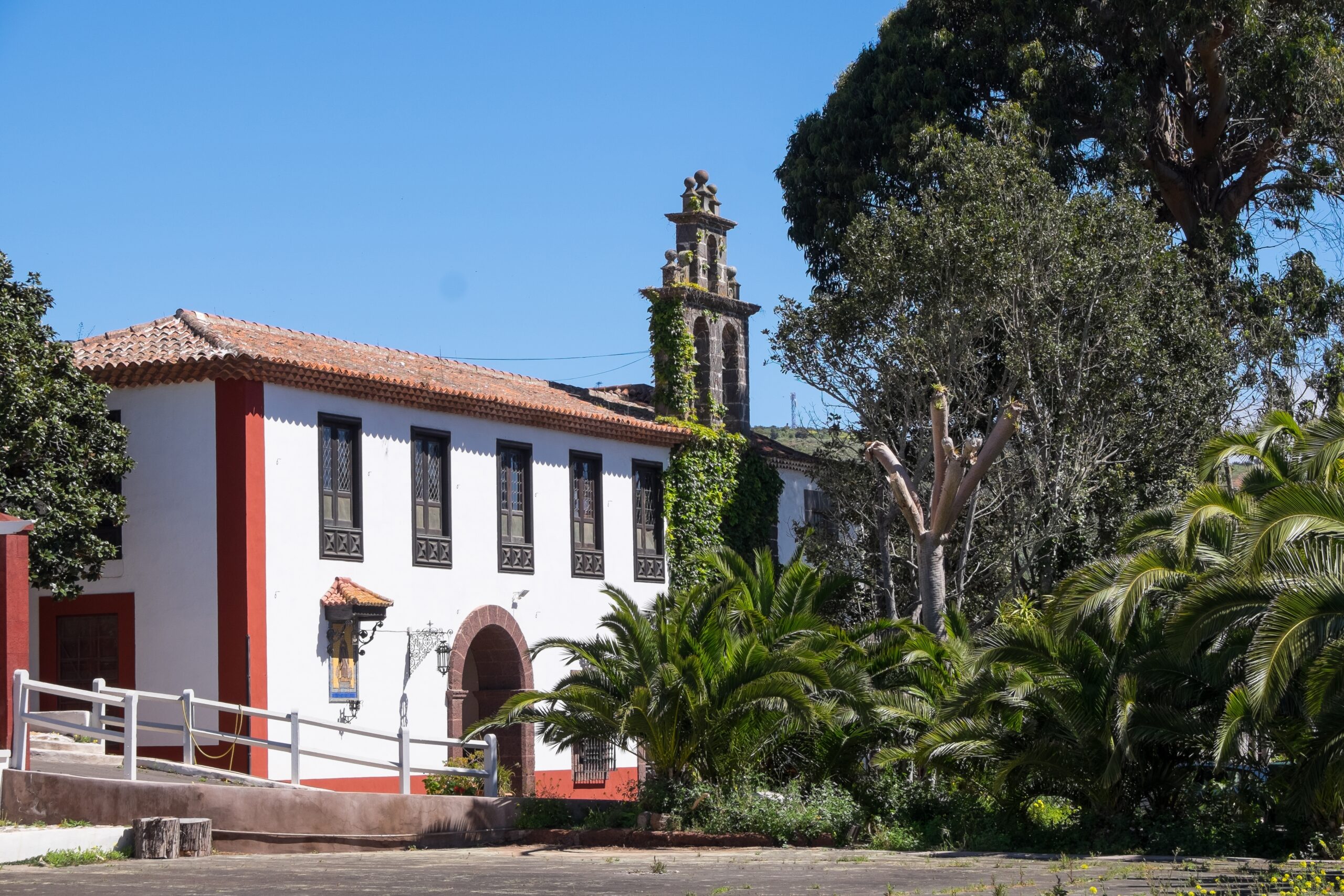 Spanish-Style Residential Property Exterior – Kings Beach Residential Beautiful Spanish-style home surrounded by lush greenery and palm trees under a clear blue sky, showcasing elegant architecture – Kings Beach Residential
